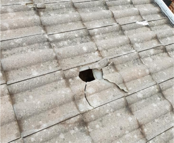 Picture of a stone roof with a hole damage on it